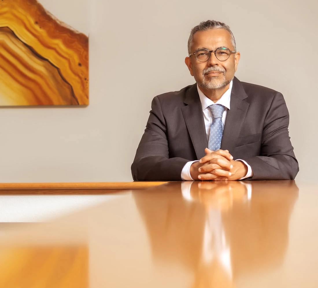 Dr. Munish Batra, board-certified plastic surgeon, seated at a conference table